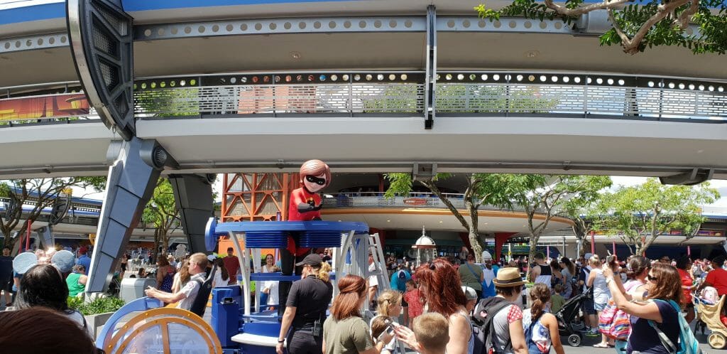 Elastigirl waves from a float surrounded by crowds at Disney World