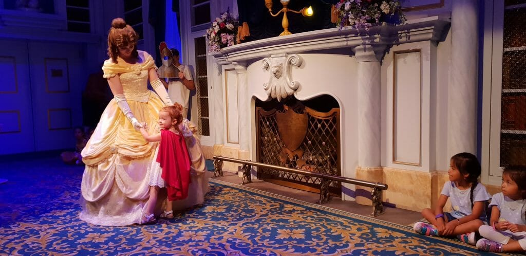 Little girl dances with characters from Beauty and Beast at Disney World