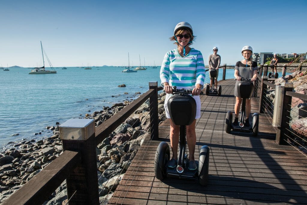 Family on segways along a seaside boardwalk at Airlie Beach