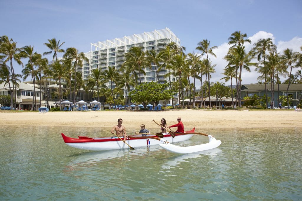 Family paddling a kayak at the beach in front of Kahala Hotel & Resort