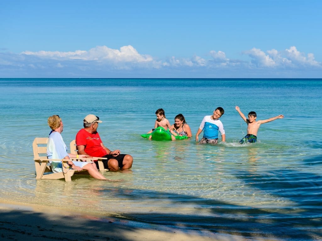Grandparents and grandkids play in shallows of Fijian beach