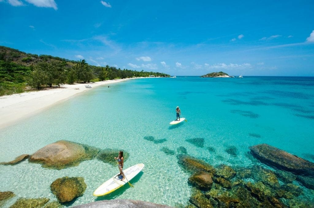 Two paddle boarders in crystal clear blue waters at Lizard Island all-inclusive resort