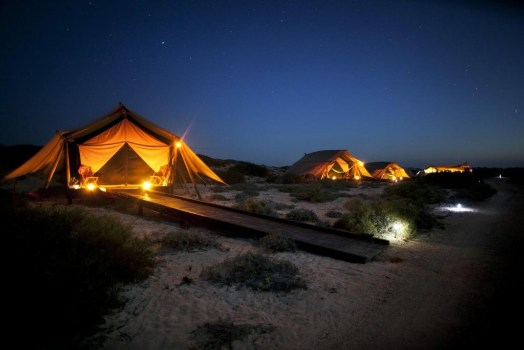 Eco-luxe camp tent set up on the beach at night at Sal Salis all-inclusive resort