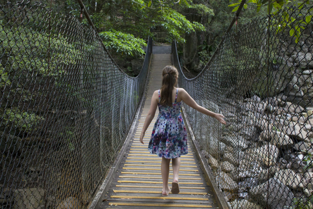 Girl walking across suspension brugde