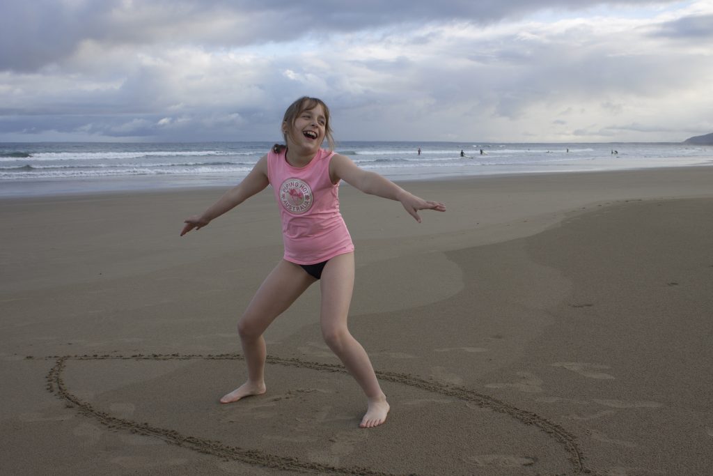 Girl pretending to surf on beach Kiama for kids
