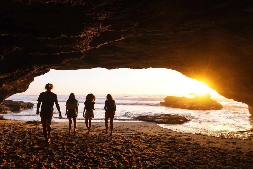silohuet of kids at sunrise at Caves Beach caves