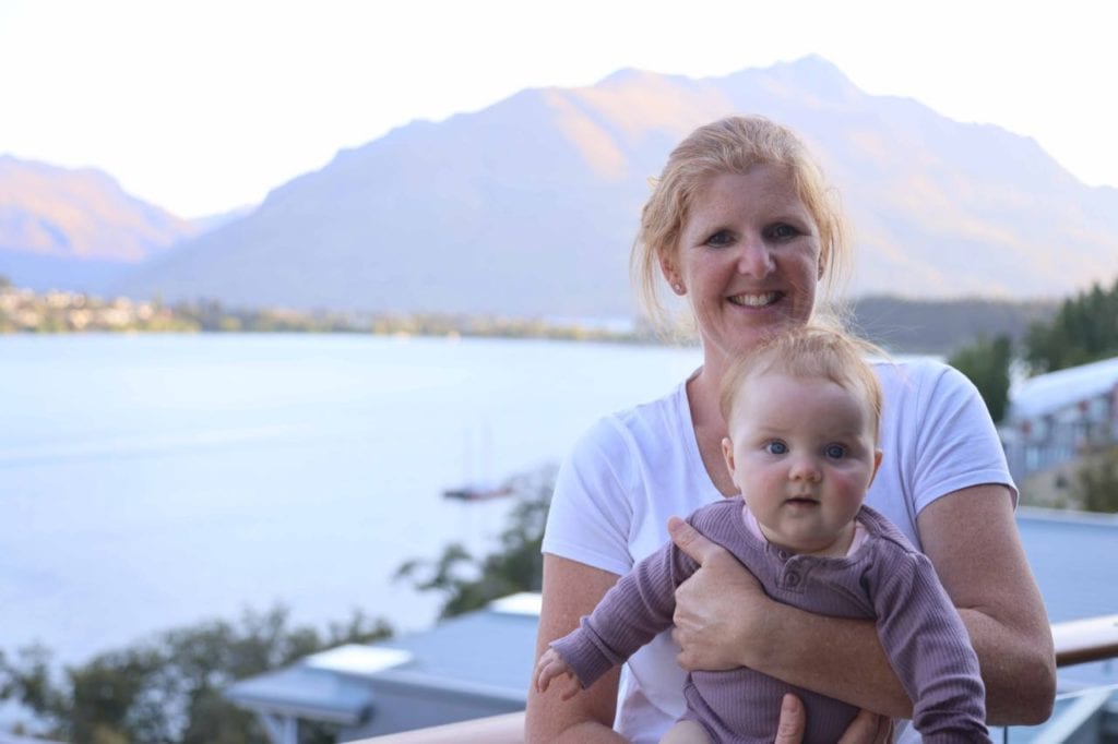 lady and a baby outside at The Rees Hotel with the Remarkables mountains in the background