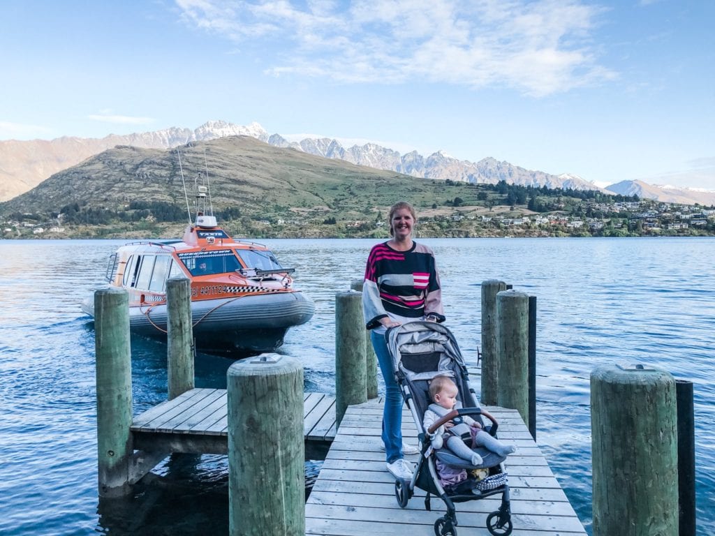 lady with a baby in a pram on a jetty waiting for a water taxi on lake wakatipu, Queenstown, New Zealand