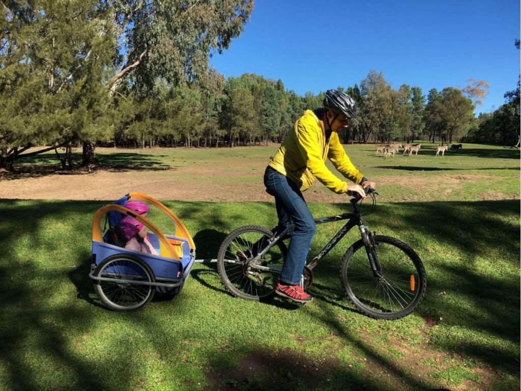 dad cycles, towing kids behind him around Taronga Western Plains Zoo