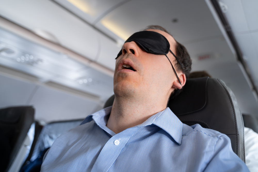 Young Man Sleeping With Sleep Mask On Airplane