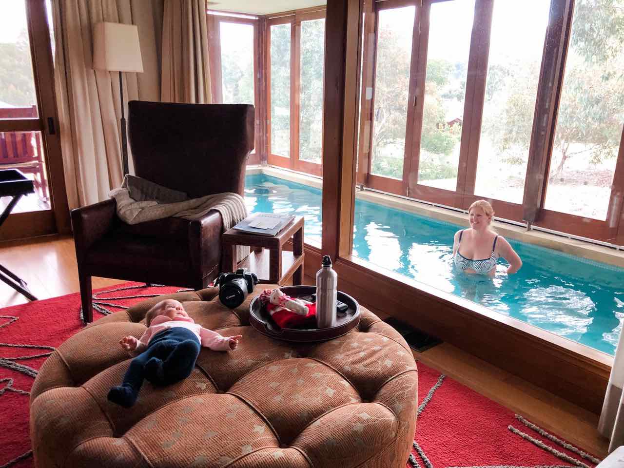 baby lying on an ottoman in the room at Emirates One & Only Wolgan Valley, while mum is in the in-room pool looking on