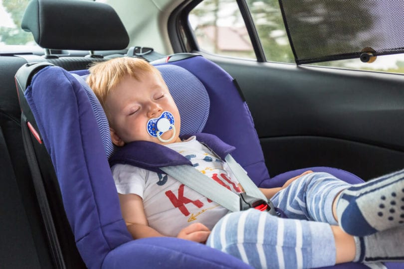 little boy with red hair sleeping in his car seat