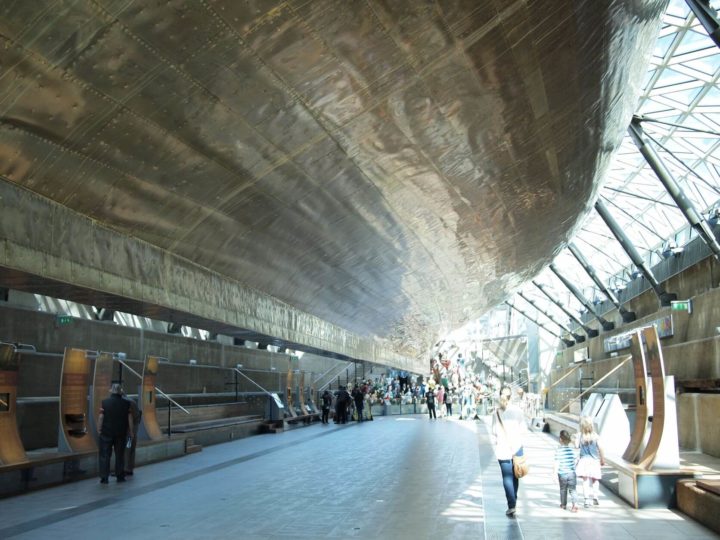A woman and two young children walk beneath the Cutty Sark hull in Greenwich, London