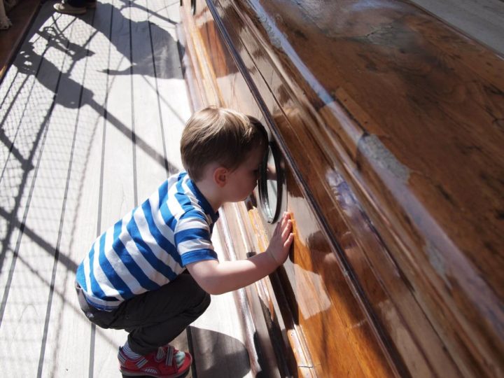 a young boy looks through the porthole of the Cutty Sark in Greenwich London