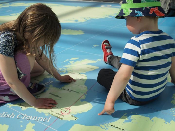 A young boy and girl point to London on a giant map on the floor at the National Maritime Museum in Greenwich, London